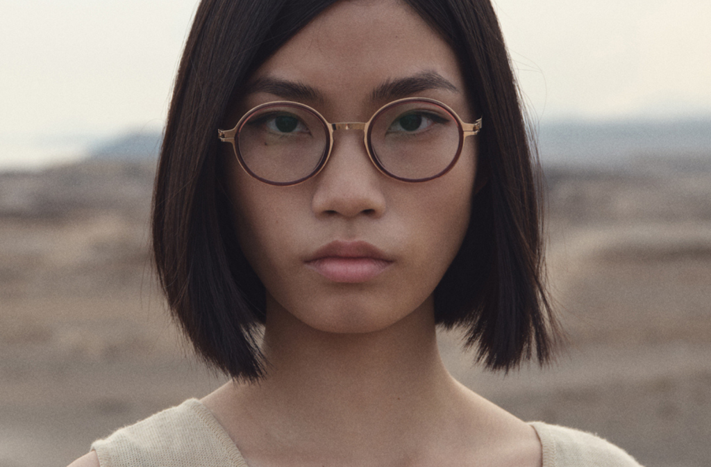 A young woman wearing Mykita Eyewear, standing outdoors