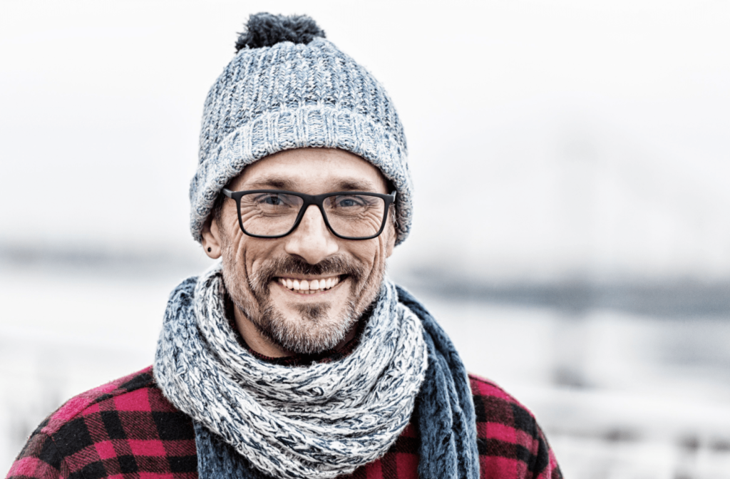 A portrait of a man in a knitted white-blue scarf and hat on cold weather is wearing glasses to protect his eyes from cold wind