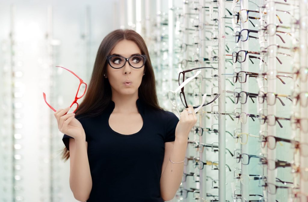 A woman is holding and choosing eyeglasses frames in an optical store