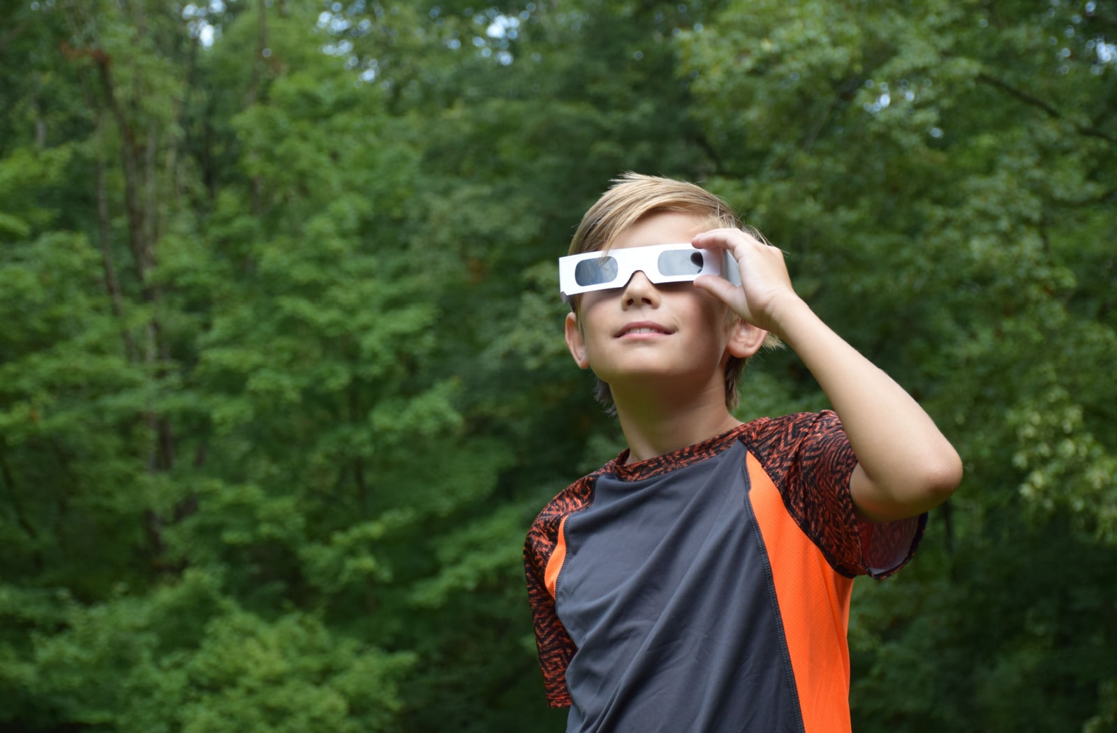 A young boy wearing solar eclipse glasses to look at the solar eclipse safely