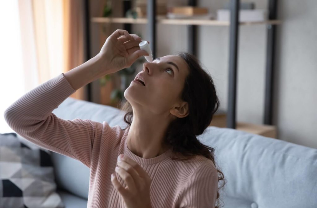 A young woman carefully using eye drops at home to find relief from her dry eye syndrome.